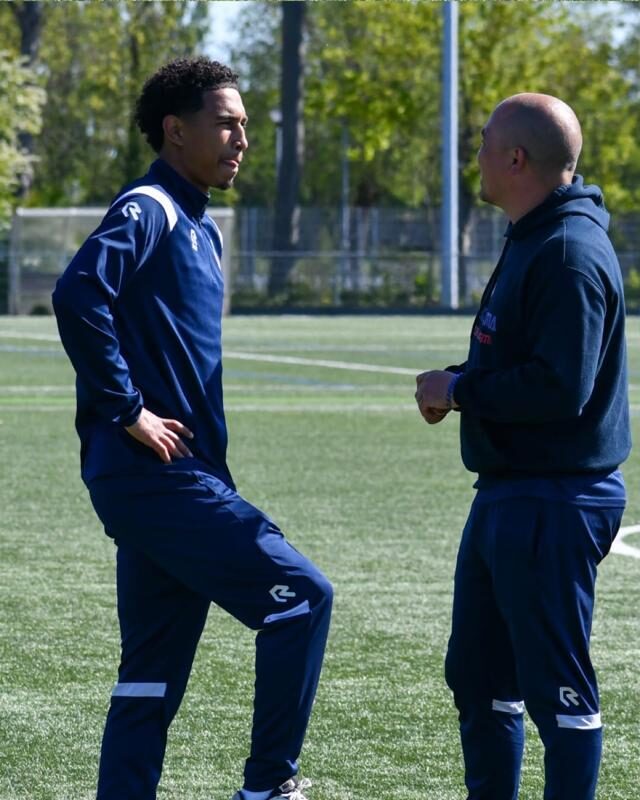 Twee trainers van Magkasama overleggen op het veld